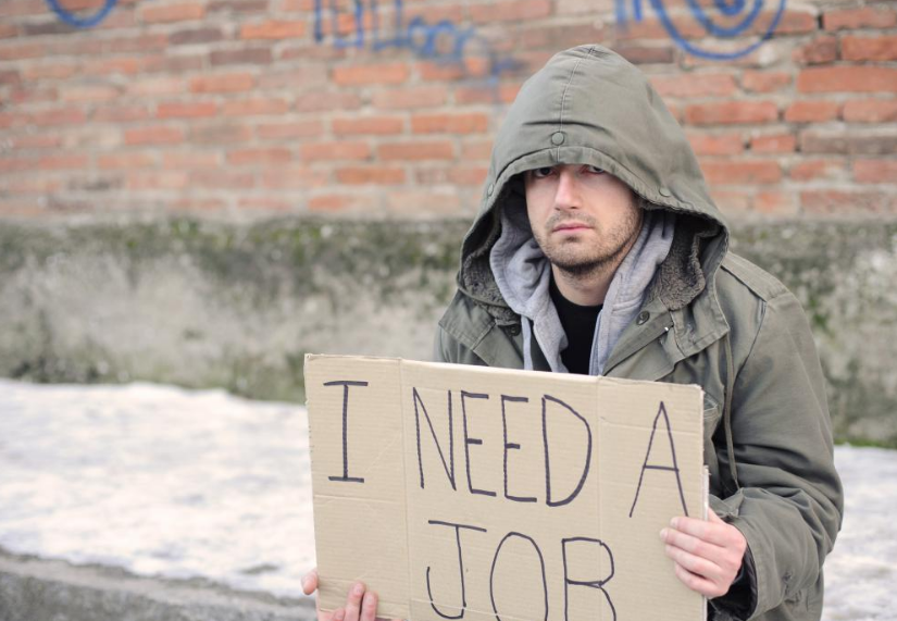 Trabajador desplazado con un letrero para buscar trabajo